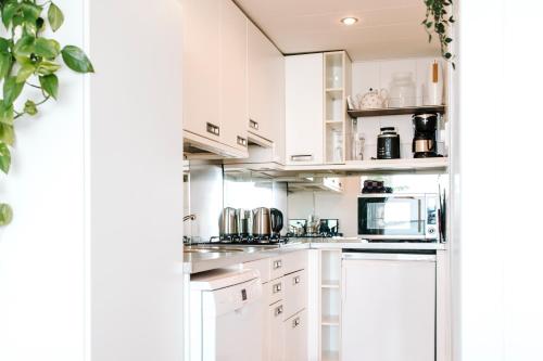 una cocina blanca con armarios y electrodomésticos blancos en Studio at Sea, en Zandvoort