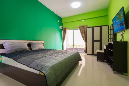 um quarto verde com uma cama e uma televisão de ecrã plano em The Bua Boutique Resort em Ban Huai Krabok