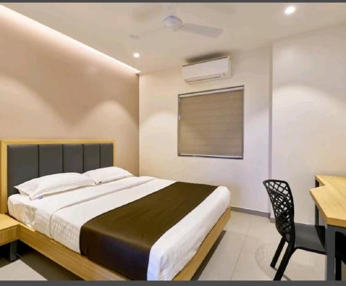a bedroom with a bed and a desk and a window at Hotel Elite Inn Kolhapur in Kolhapur