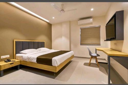 a bedroom with a bed and a desk and a television at Hotel Elite Inn Kolhapur in Kolhapur
