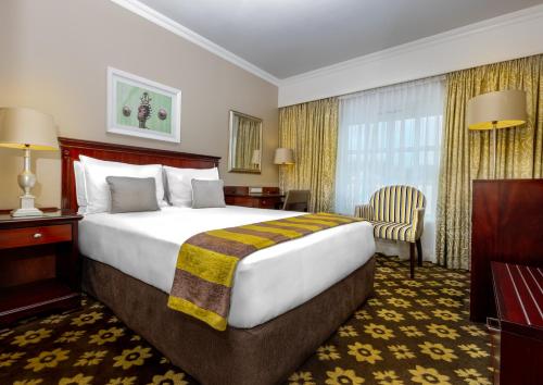 a hotel room with a large bed and a chair at Hemingways Hotel in East London
