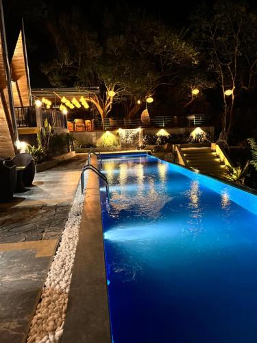 a blue swimming pool at night with lights at Sundown Lake Hotel & Spa in Habarana