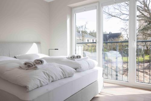 a white bedroom with two beds and a large window at Bootsmann Escapes in Böhl