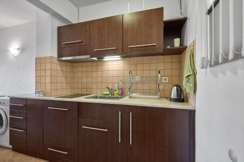 una cocina con armarios de madera y fregadero en Charming 2BD Guest House in Sozopol en Burgas