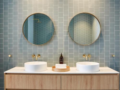 dois lavatórios numa casa de banho com espelhos na parede em Green Valley Hotel em Mount Pritchard