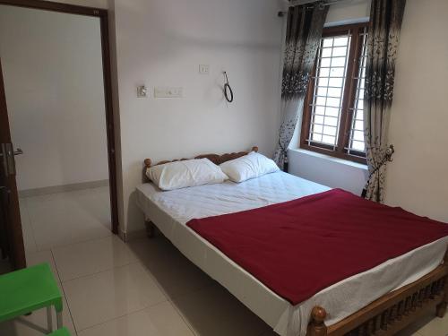 een slaapkamer met een bed met een rode deken en een raam bij Mubarak Family Restaurant in Kuzhittura