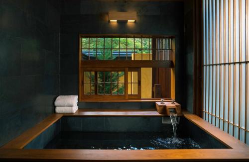 a bathroom with a bath tub with a window at Onsen at Moncham in Mae Rim