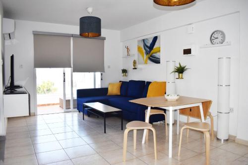 a living room with a blue couch and a table at Sunny Rooftop in Ayia Napa 91Sqm Terrace Delight! in Ayia Napa