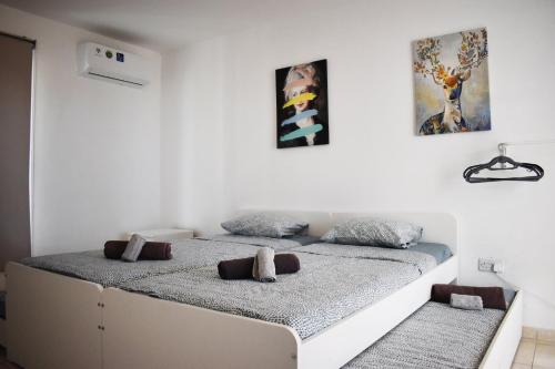two beds in a white room with paintings on the wall at Sunny Rooftop in Ayia Napa 91Sqm Terrace Delight! in Ayia Napa
