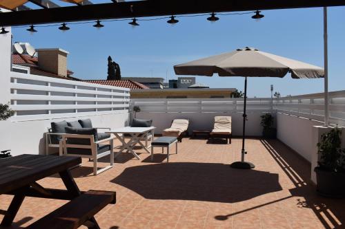 a patio with a table and an umbrella on a roof at Sunny Rooftop in Ayia Napa 91Sqm Terrace Delight! in Ayia Napa