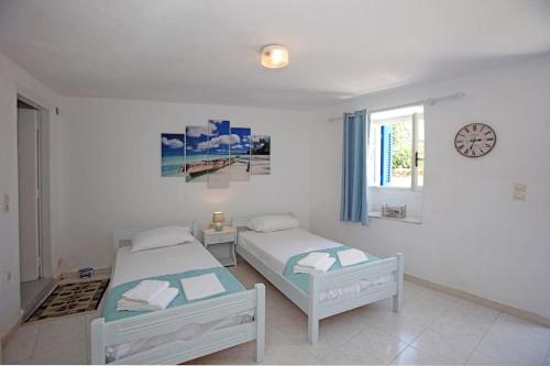 a bedroom with two beds and a clock on the wall at Paraporti Rooms in Andros