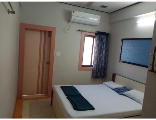 Habitación pequeña con cama y ventana en Hotel Trimurti, Dwarka, en Dwarka