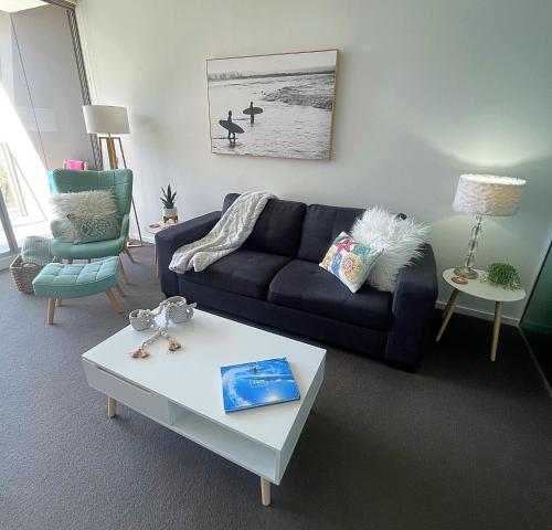 a living room with a blue couch and a coffee table at AQUA 306 POOLSIDE Luxury Apartment , Honeysuckle, NEWCASTLE FREE Parking in Newcastle