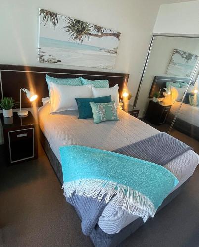 a bedroom with a large bed with blue and white pillows at AQUA 306 POOLSIDE Luxury Apartment , Honeysuckle, NEWCASTLE FREE Parking in Newcastle