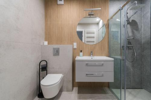 Un baño con inodoro, lavabo y espejo. en Letnica - Seaside Apartments, en Gdansk