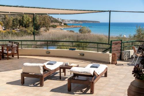 a patio with two chairs and a table and the ocean at Coastal Dream beachView Jacuzzi& sauna free parking WiFi 2 bedroom in Amoudara Lasithiou