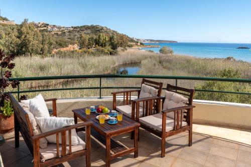 a patio with chairs and a table with a view of the ocean at Coastal Dream beachView Jacuzzi& sauna free parking WiFi 2 bedroom in Amoudara Lasithiou