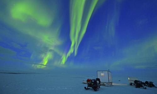 eine Gruppe von drei Schneemobilen im Schnee unter der Aurora in der Unterkunft Authentic Sami Reindeer Herding Adventure in Arctic Norway in Kautokeino