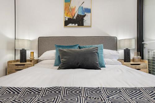 1 dormitorio con 1 cama blanca grande con almohadas azules en Stay Near Botanic Garden with Gym, Sauna & Parking en Melbourne