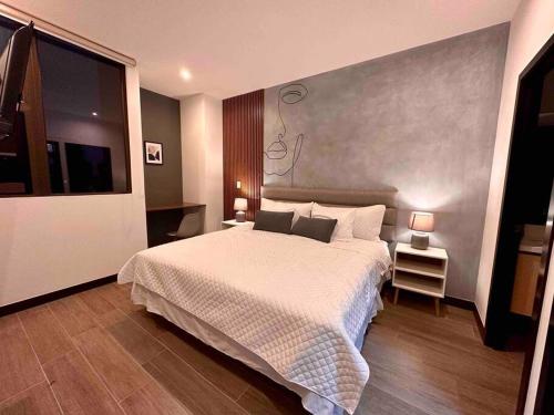 a bedroom with a large white bed and a television at New Modern Apartment with pool in Guatemala