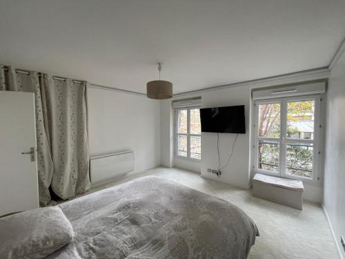 - une chambre blanche avec un lit et une télévision dans l'établissement Logement en Hôtel Particulier - 3mn Paris et métro, à Boulogne-Billancourt