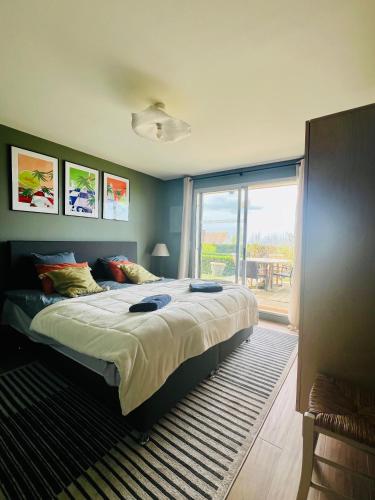 une chambre avec un grand lit et une grande fenêtre dans l'établissement Grand rez de jardin-terrasse avec vue sur la mer - 2 chambres, à Blonville-sur-Mer