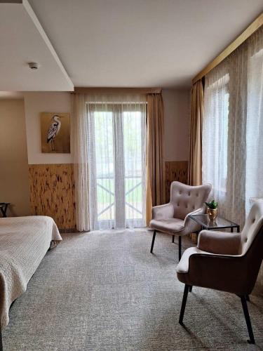 a bedroom with a bed and a chair and a window at Duna Garden Hotel in Budapest