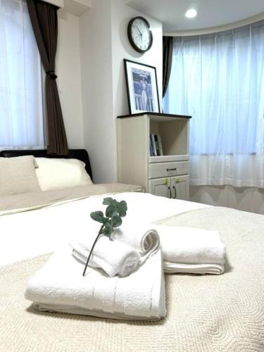 a bedroom with two beds with towels and a clock at Kyo Sai 浅草2F浅草寺まで徒步約10分 in Tokyo