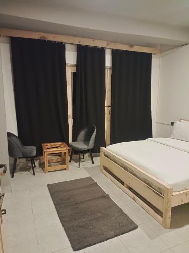 a bedroom with a bed and two chairs and a table at BONO MOTELS in Nārān