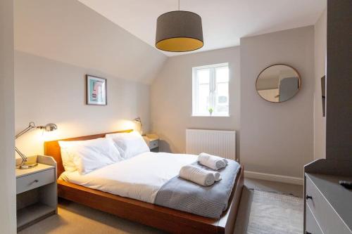 a bedroom with a bed with white sheets and a mirror at Chapel View in Loughborough