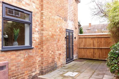 a brick house with a door and a wooden fence at Chapel View in Loughborough