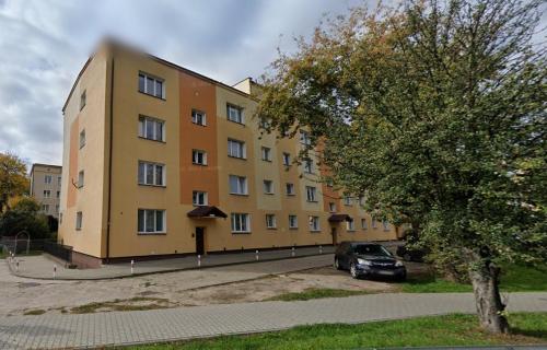 un bâtiment jaune avec une voiture garée devant lui dans l'établissement Przytulne mieszkanie z balkonem dostęp na kod, à Radom