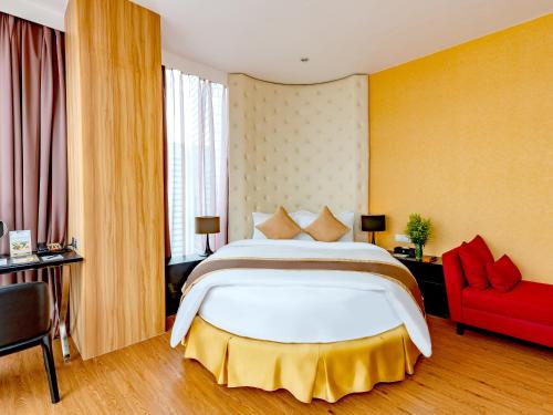 1 dormitorio con 1 cama grande y 1 silla roja en Bay Hotel Ho Chi Minh, en Ho Chi Minh