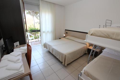 a hotel room with two beds and a balcony at Hotel Laura in Bibione