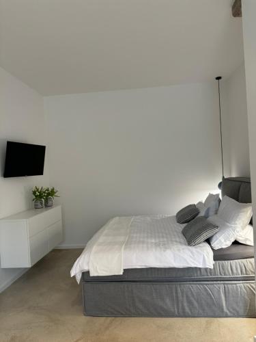 a white bedroom with a bed and a tv at Sievershof Strandbar in Wietzendorf