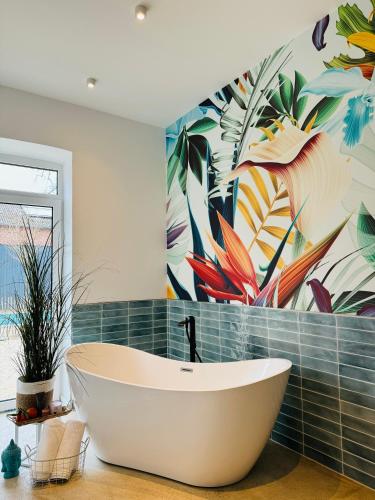 a bathroom with a tub and a mural of flowers at Sievershof Strandbar in Wietzendorf