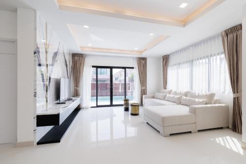 Una sala de estar con un sofá blanco y un televisor. en 4 bedrooms, 4 bathrooms, villa with swimming pool, free Wi-Fi, party available, en Ban Pho Sa