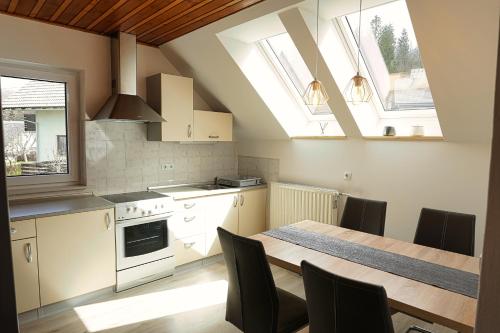 a kitchen with a table and chairs and two windows at Apartments Jelka in Bohinj