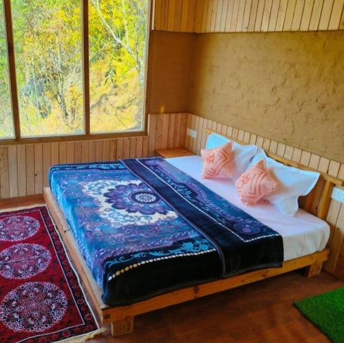 a bed in a room with two pillows on it at Pyare Cafe Cottages And Tents in Gushaini