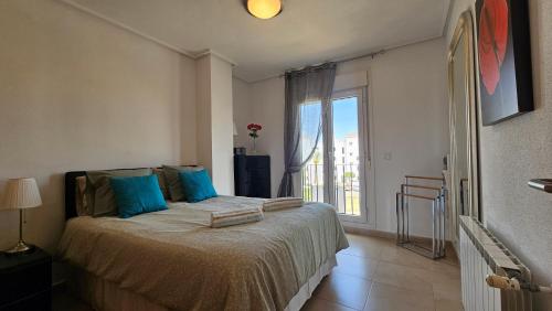 ein Schlafzimmer mit einem Bett mit blauen Kissen und einem Fenster in der Unterkunft Stunning views and south facing at La Torre Golf Resort - AN1221LT in Torre-Pacheco