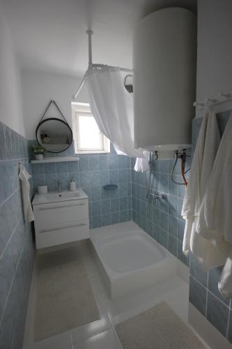 a blue tiled bathroom with a sink and a mirror at Cinege Vendégház Szekszárd in Szekszárd