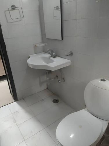 a white bathroom with a toilet and a sink at Apartment in Omaxe, Vrindavan in Mathura