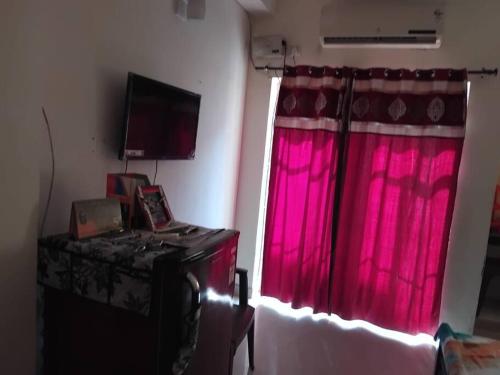 a room with a red curtain and a window at Apartment in Omaxe, Vrindavan in Mathura