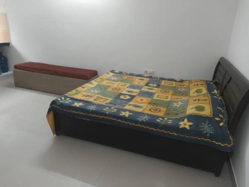 a bed with a quilt on it with a box at Apartment in Omaxe, Vrindavan in Mathura