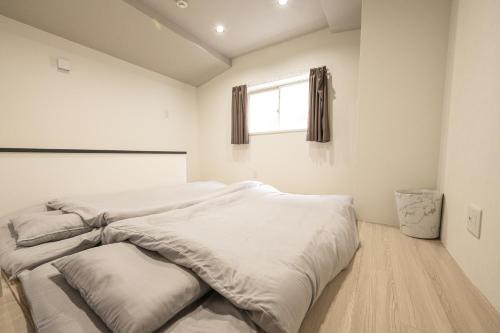 a bedroom with two white beds and a window at 匠の家 大阪城近くの高級感あふれる吹き抜けの家 A Luxurious Home with a Grand Atrium Near Osaka Castle in Osaka