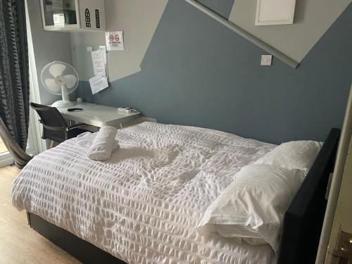 a bedroom with a white bed with a desk and a chair at Luxurious Soft Water Air Conditioning TV BITCOIN in London