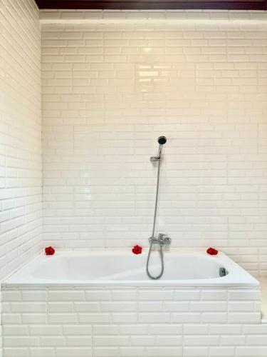 a white bath tub with red flowers in a bathroom at Bupon House Ubud in Gianyar