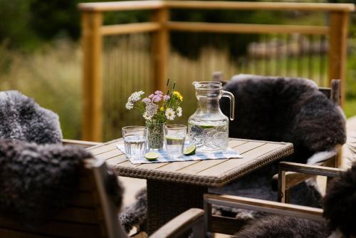 a table with glasses and a jug and flowers on it at Ödevata Gårdshotell in Emmaboda