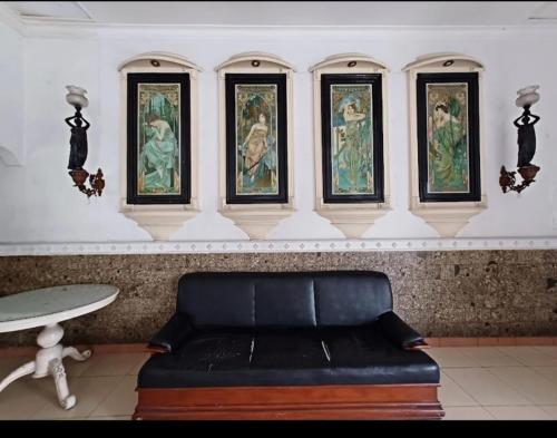 marini hotel في Colomadu: أريكة في غرفة بها لوحات على الحائط