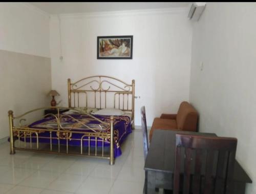 marini hotel في Colomadu: غرفة نوم بسرير وكرسي وأريكة